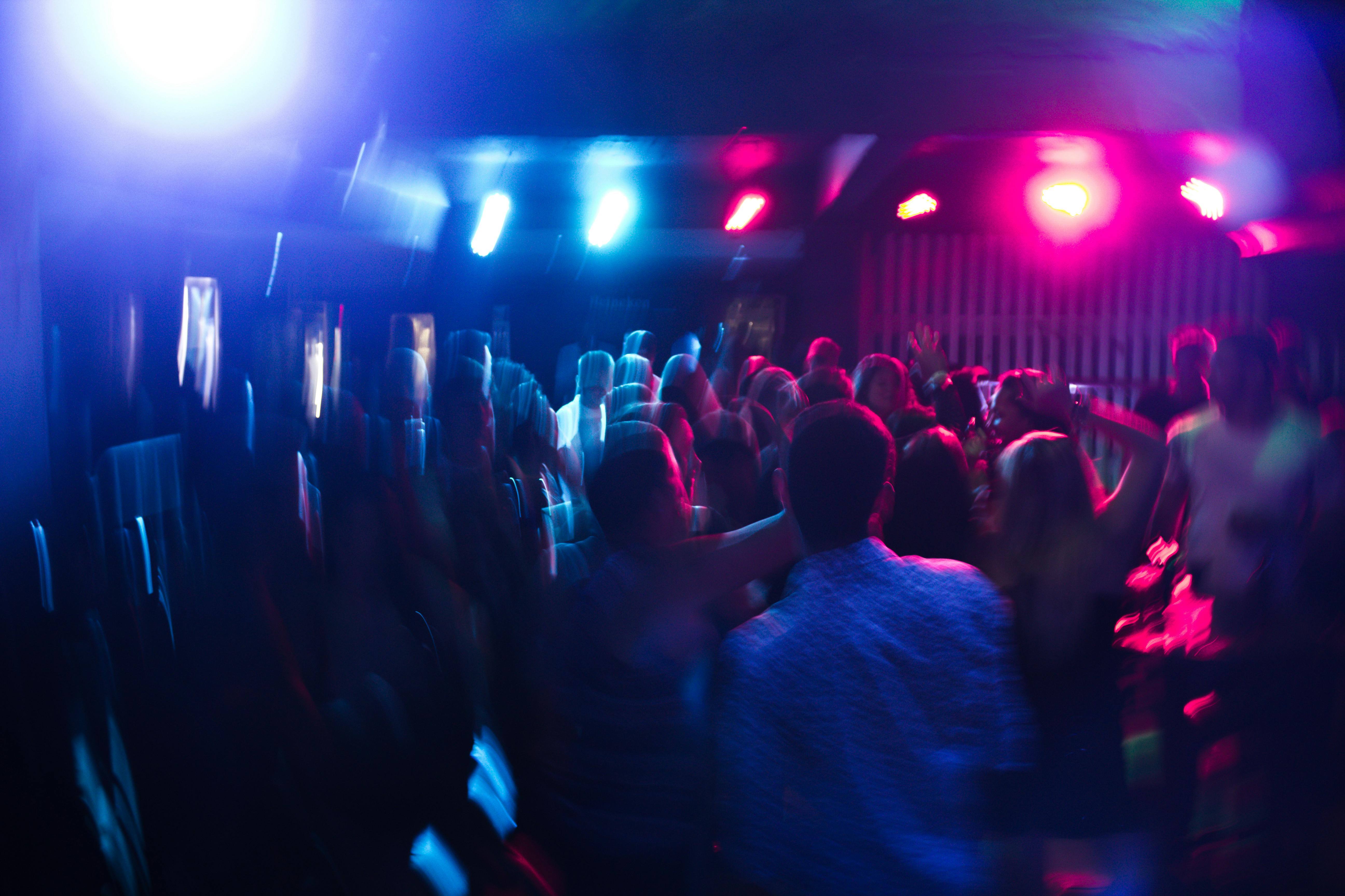 Vibrant party atmosphere with people dancing under colorful blue and pink lighting